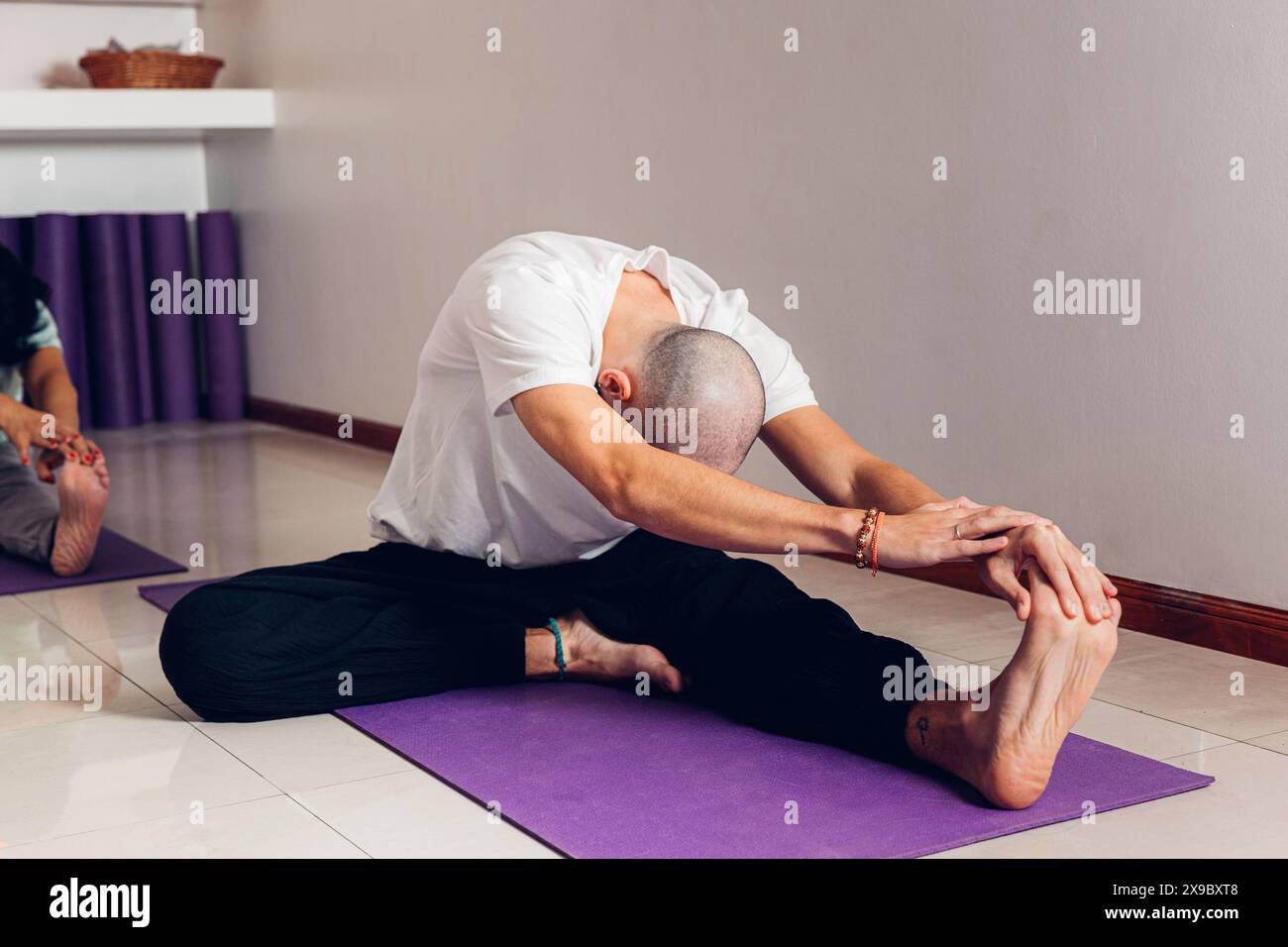 Jeune homme en classe en classe faisant le yoga Janu Sirsasana pose : la tête au genou Banque D'Images
