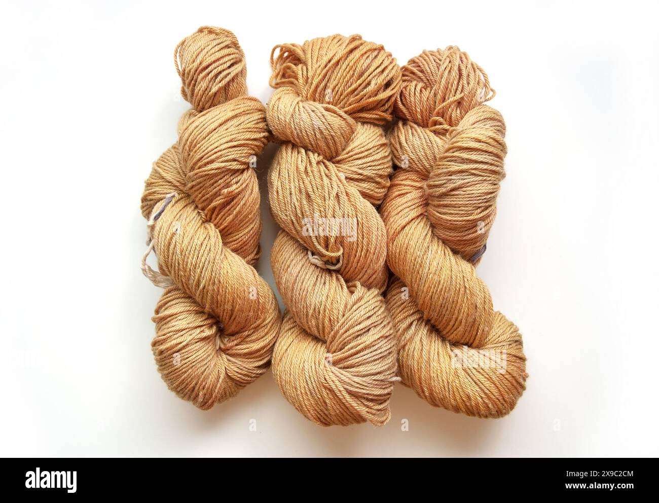 Photo de table de trois anses de fil beige tordues isolées sur un fond blanc, pose à plat d'écheveaux de laine teints à la main Banque D'Images