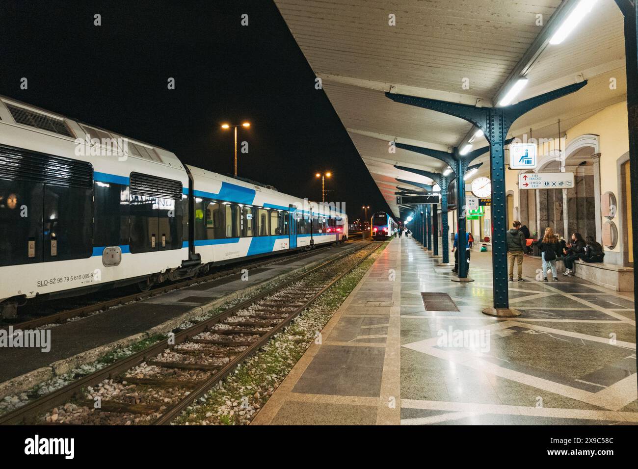 Un train régional blanc et bleu à la gare de Ljubljana, Slovénie, la nuit Banque D'Images