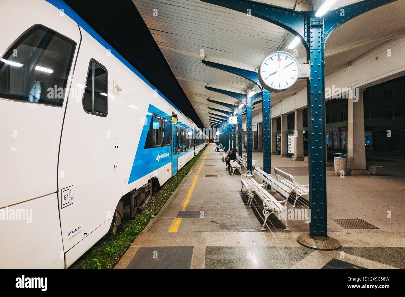 Un train régional blanc et bleu à la gare de Ljubljana, Slovénie, la nuit Banque D'Images
