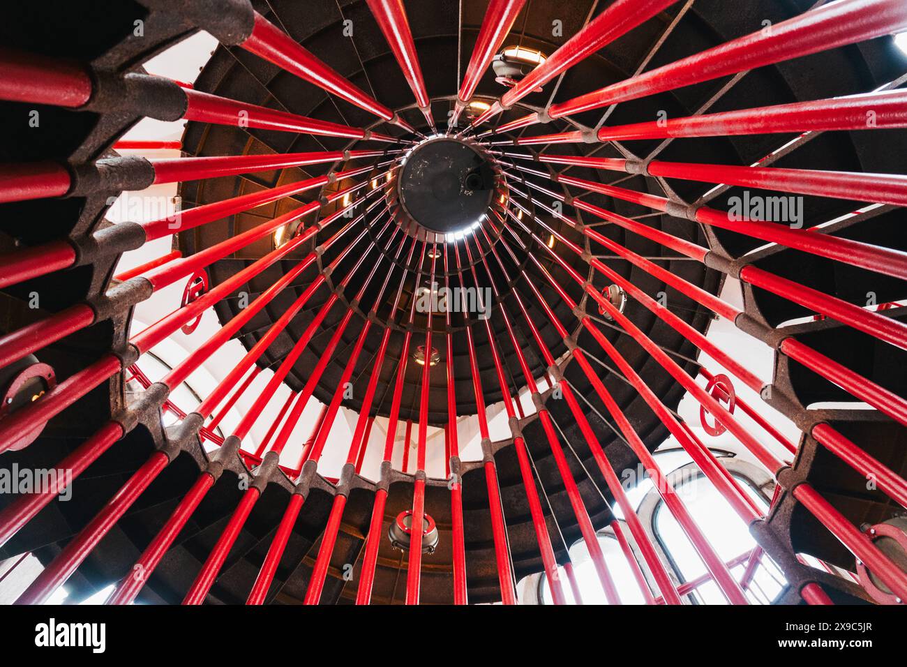 Un escalier en colimaçon à l'intérieur du château de Ljubljana, menant à l'une des tours. Un bannister rouge vif se connecte à des marches en bois à motifs complexes Banque D'Images