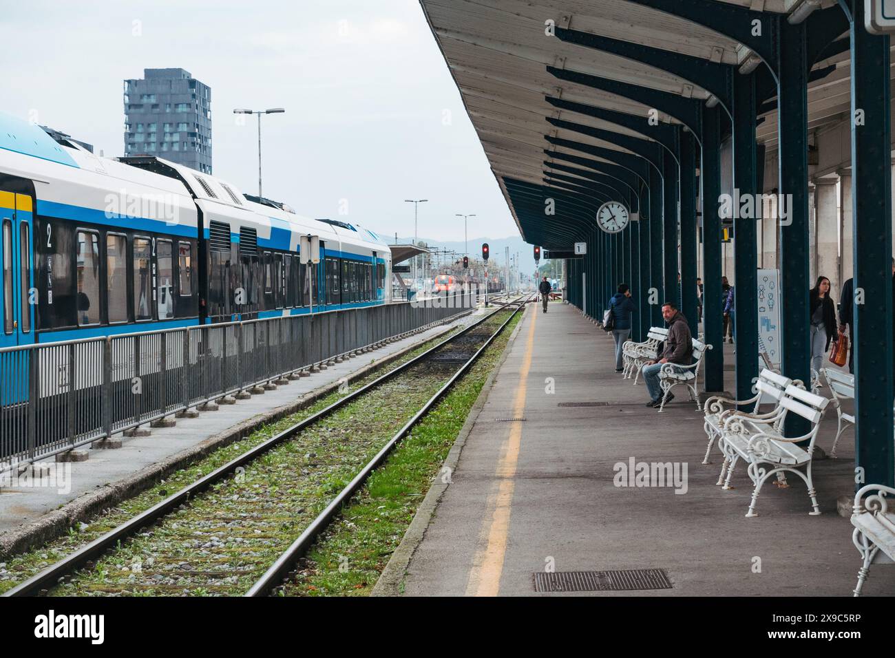 Un train régional des chemins de fer slovènes tourne au ralenti sur une voie ferrée à la gare de Ljubljana, en Slovénie. Un abri pend au-dessus de la plate-forme Banque D'Images