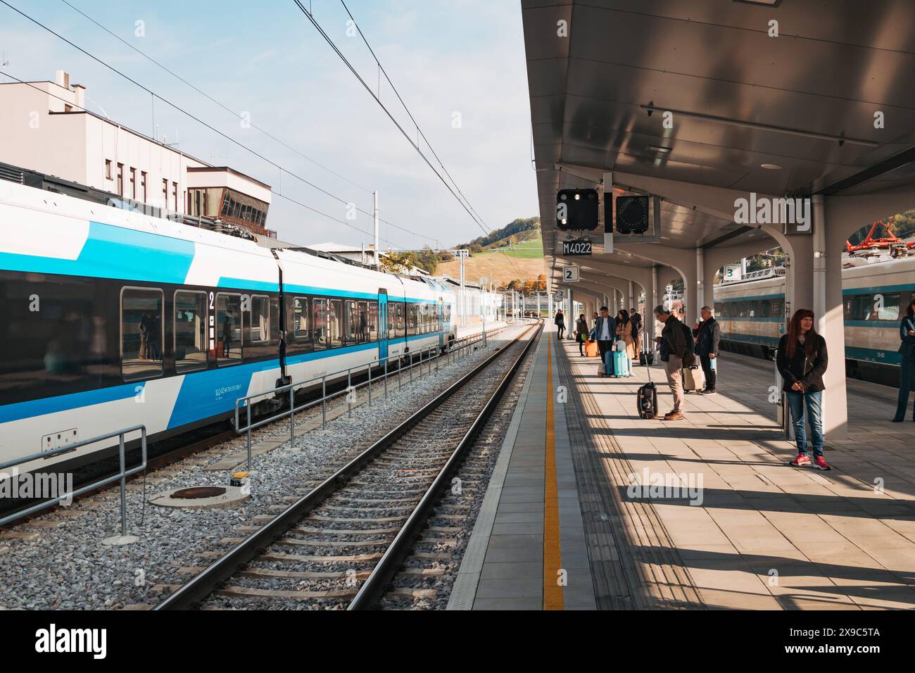 Un train moderne se trouve sur le quai de la gare de Maribor en Slovénie alors que les passagers attendent leur départ. Banque D'Images