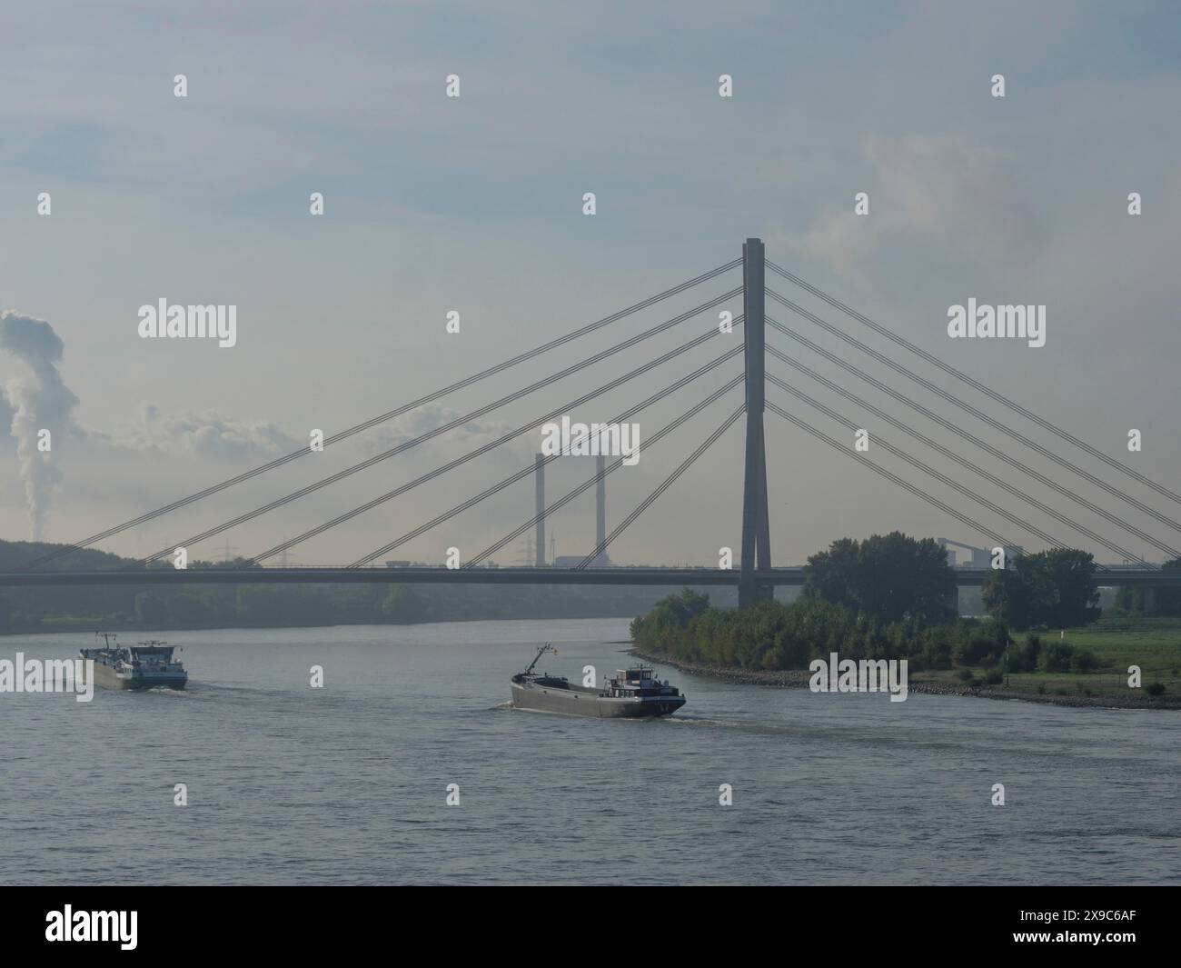 Scène avec pont sur le Rhin, bateaux et fond industriel sous ciel bleu, trafic maritime sur le Rhin près de Wesel sur un matin brumeux Banque D'Images