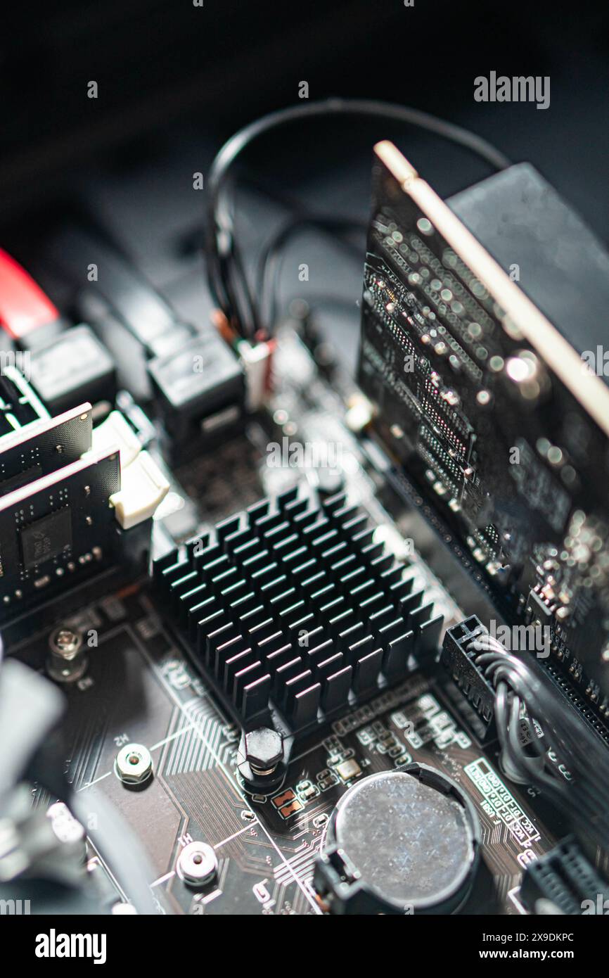 Vue rapprochée d'une carte mère d'ordinateur avec divers composants, y compris un dissipateur de chaleur, une carte de circuit imprimé et des connecteurs. Banque D'Images