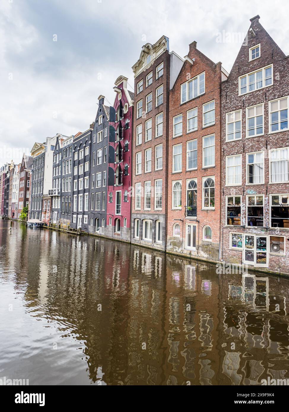 Les maisons colorées, charmantes et minces en pain d'épice de Damrak photographiées sous un ciel nuageux à Amsterdam, aux pays-Bas, le 27 mai 2024. Banque D'Images
