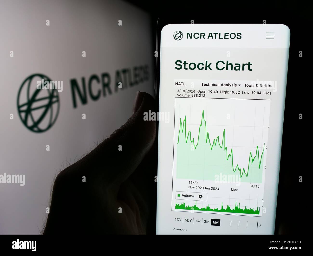 Personne tenant un smartphone avec le site Web de la société de services financiers américaine NCR Atleos Corporation devant le logo. Concentrez-vous sur le centre de l'écran du téléphone. Banque D'Images