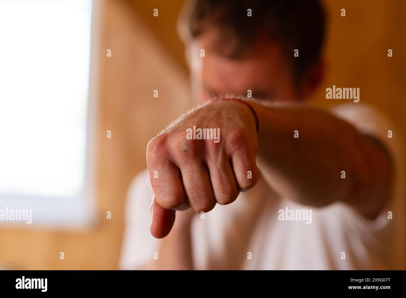 Un homme se tient debout dans une posture de boxe, avec une expression sérieuse. Il semble prêt à agir, faisant preuve d'assurance et de détermination Banque D'Images