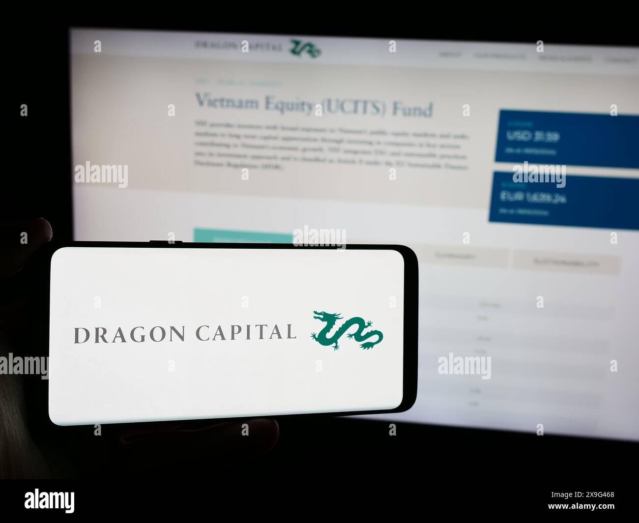 Personne tenant le téléphone portable avec le logo de la société vietnamienne Dragon Capital Group Limited devant la page Web de l'entreprise. Concentrez-vous sur l'affichage du téléphone. Banque D'Images