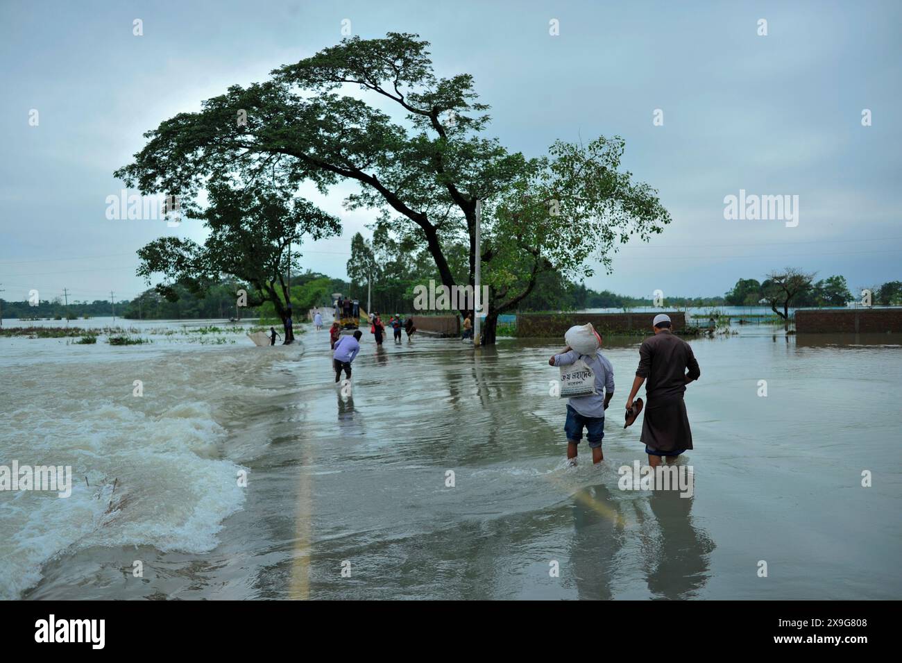 Sylhet, Bangladesh. 30 mai 2024. Les gens luttent pour patauger sur la route principale inondée de Lafnaut, dans la région de Goanghat upazila, en raison des fortes pluies qui ont suivi le passage du cyclone Remal au Bangladesh. Le 30 mai 2024 à Sylhet, Bangladesh. (Photo de MD Rafayat Haque Khan/ Eyepix Group/Sipa USA) crédit : Sipa USA/Alamy Live News Banque D'Images