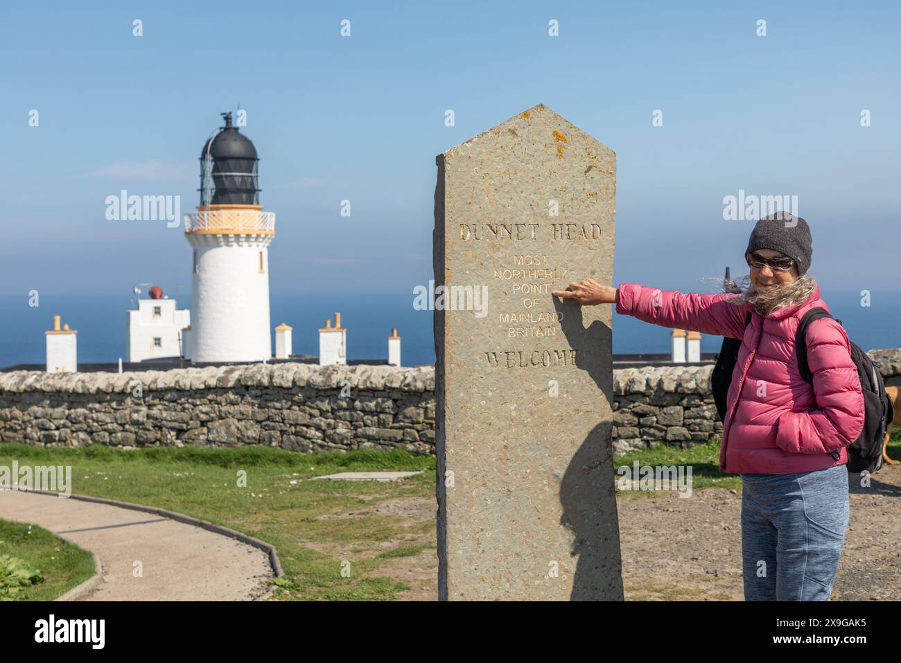 Un touriste pointe vers un marqueur à Dunnet Head, dans le nord de l'Écosse, notant le point le plus septentrional du continent écossais et de l'île de Grande-Bretagne. Banque D'Images