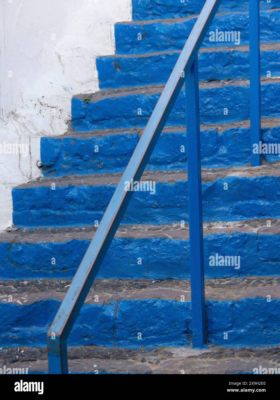 Gros plan d'un escalier en pierre bleue avec balustrade en métal et fond blanc, l'île volcanique de Santorin avec des maisons et des églises bleues et blanches Banque D'Images