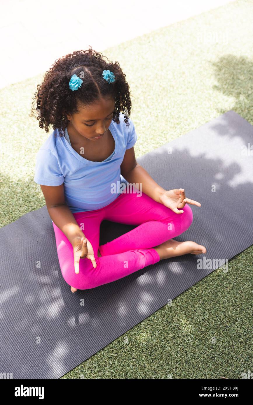 Une fille biraciale pratique le yoga à l'extérieur à l'école, avec un espace de copie Banque D'Images