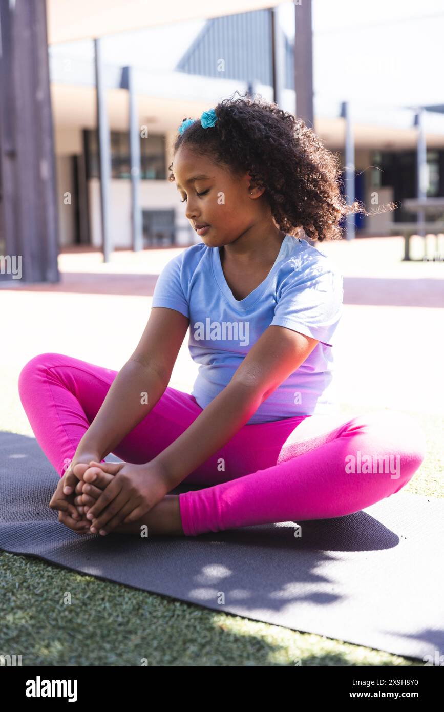 Une fille biraciale pratique le yoga à l'extérieur à l'école Banque D'Images