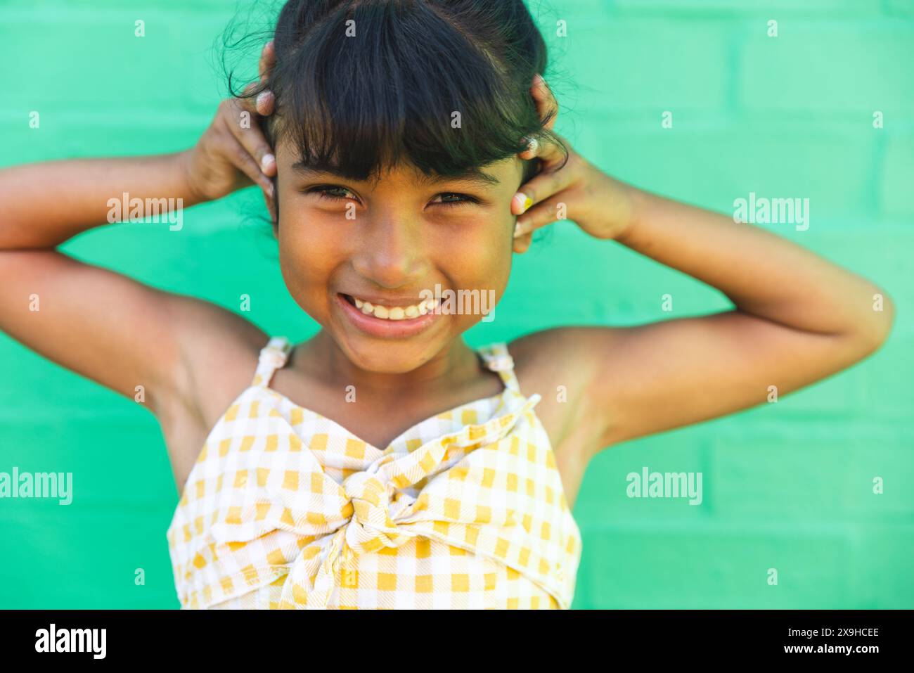 Fille biraciale sourit brillamment sur un fond vert Banque D'Images