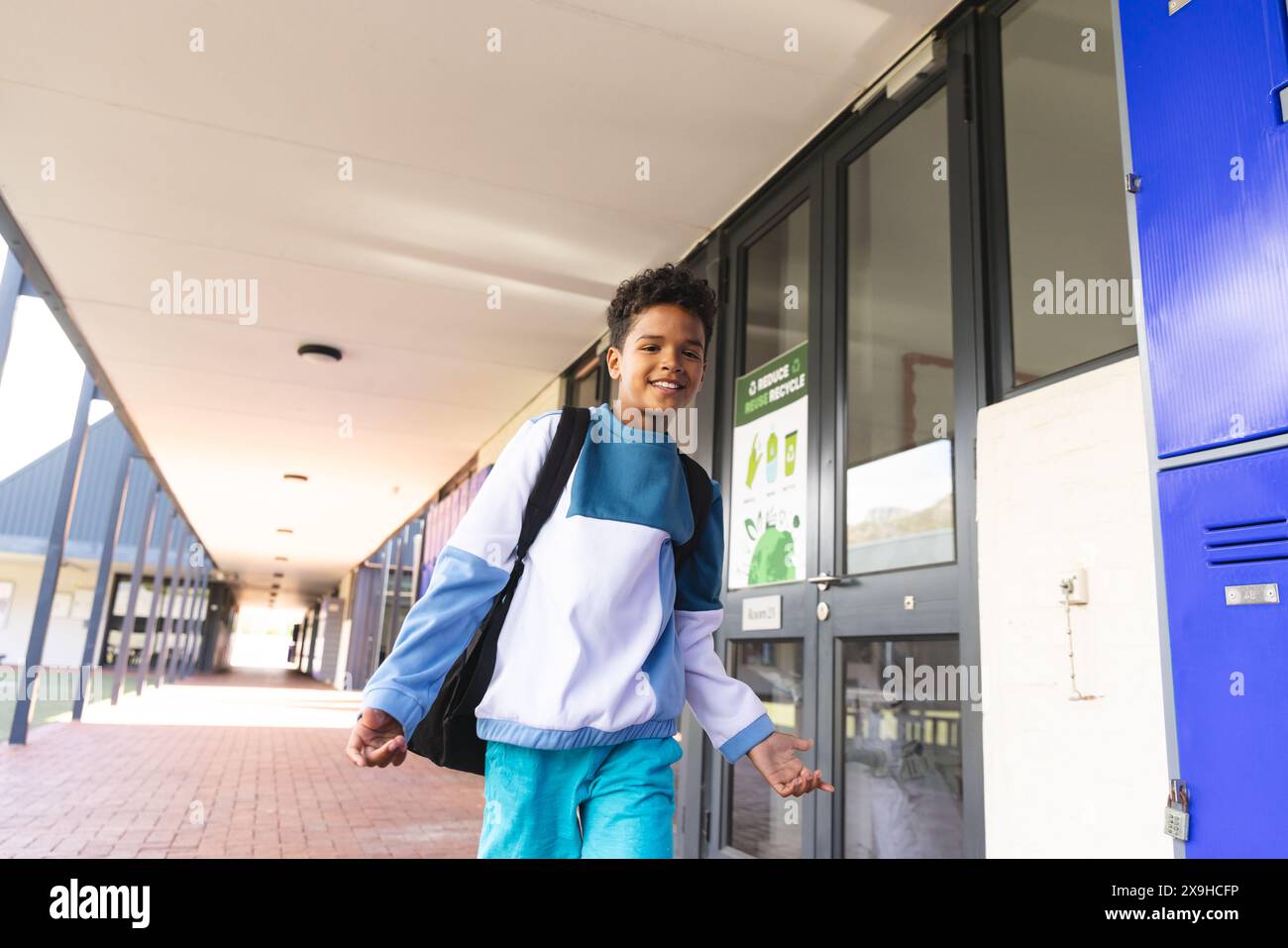 Garçon biracial debout dans un couloir d'école, avec espace de copie Banque D'Images