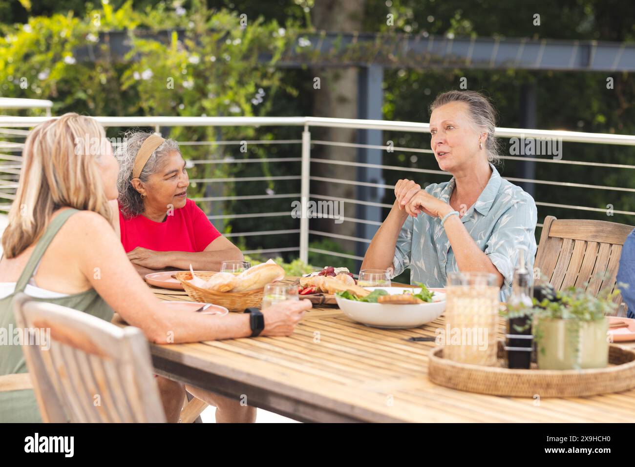 Diverses amies seniors portant des vêtements décontractés, discutant autour d'un repas à l'extérieur Banque D'Images