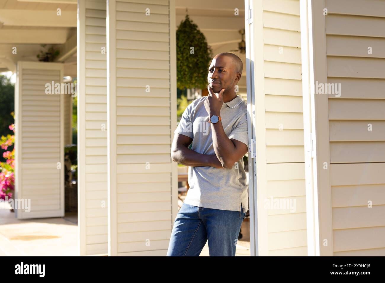 Dehors, jeune homme afro-américain debout sur le porche, regardant réfléchi Banque D'Images