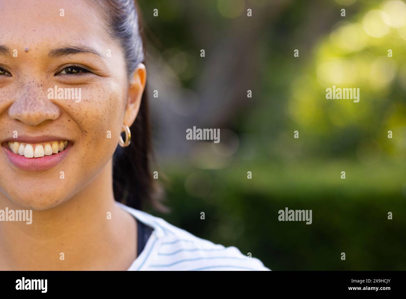 À l'extérieur, jeune femme biraciale souriant avec une végétation luxuriante et des arbres autour d'elle, copiez l'espace Banque D'Images