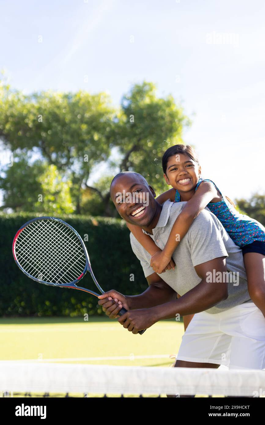 En plein air, père et fille diversifiés jouissant du tennis ensemble Banque D'Images