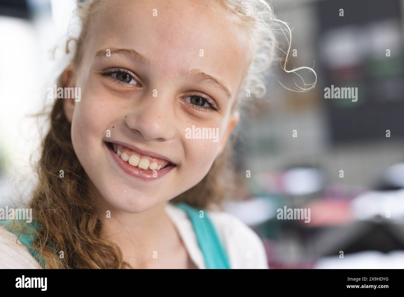 Fille caucasienne, cheveux blonds bouclés, sourires montrant des taches de rousseur en classe Banque D'Images