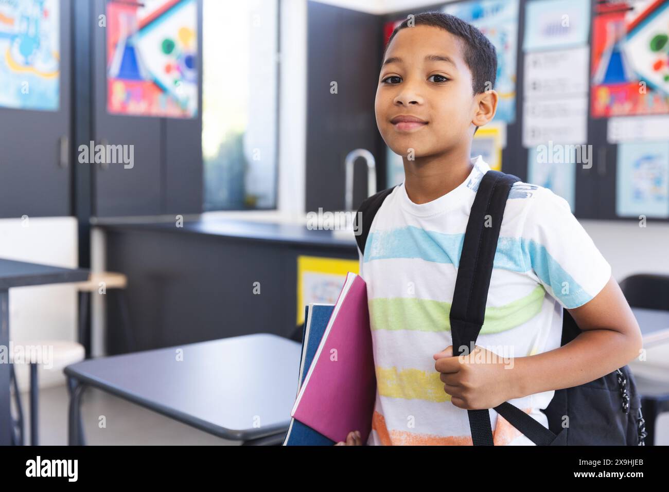 Garçon biracial se tient confiant dans une salle de classe à l'école Banque D'Images