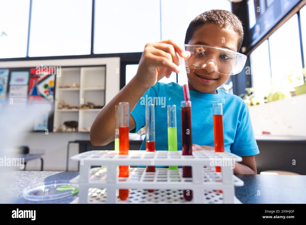 Biracial Boy mène une expérience dans la classe de science à l'école Banque D'Images