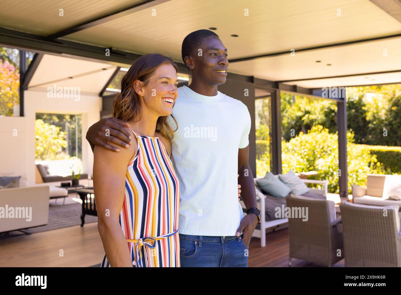 Un jeune couple diversifié à la maison, debout ensemble, souriant Banque D'Images