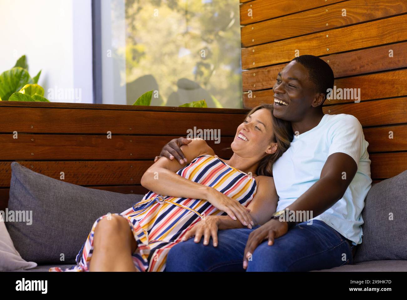Un jeune couple diversifié se relaxant à la maison le jour ensoleillé Banque D'Images