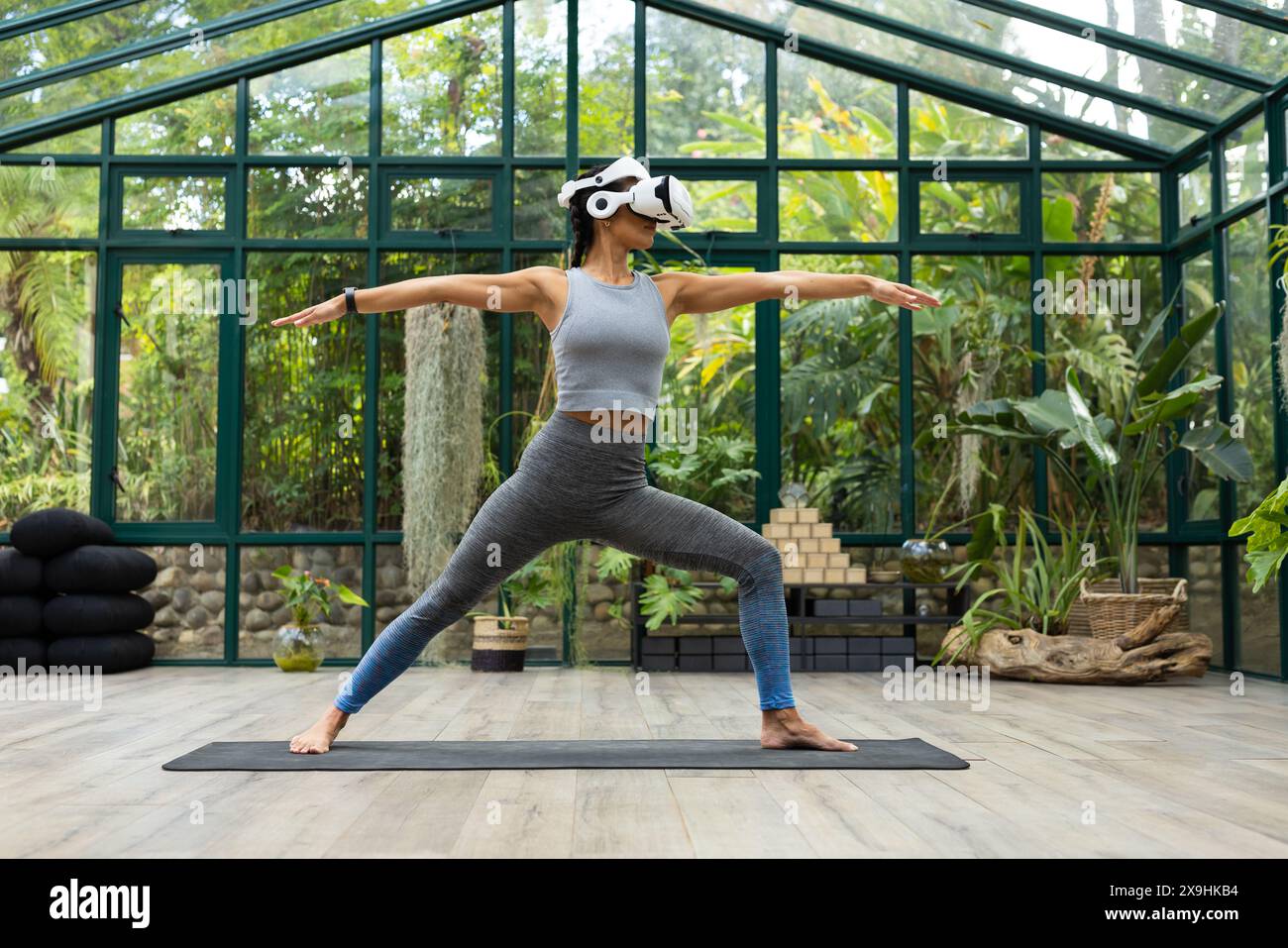 Pacific Islander femme dans le casque VR pratique le yoga au Glass House Studio Banque D'Images