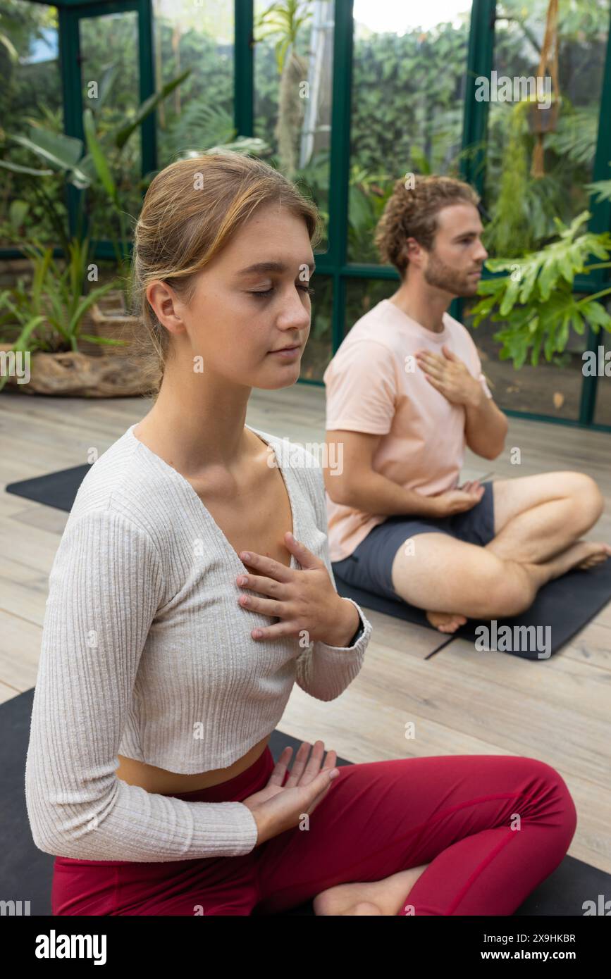 Au Glass House Studio, les étudiants de yoga caucasiens pratiquent en serre Banque D'Images