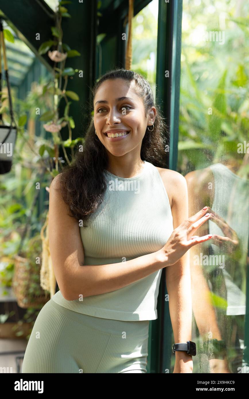 Au Glass House Studio, étudiante de yoga biraciale pratiquant dans une serre ensoleillée Banque D'Images
