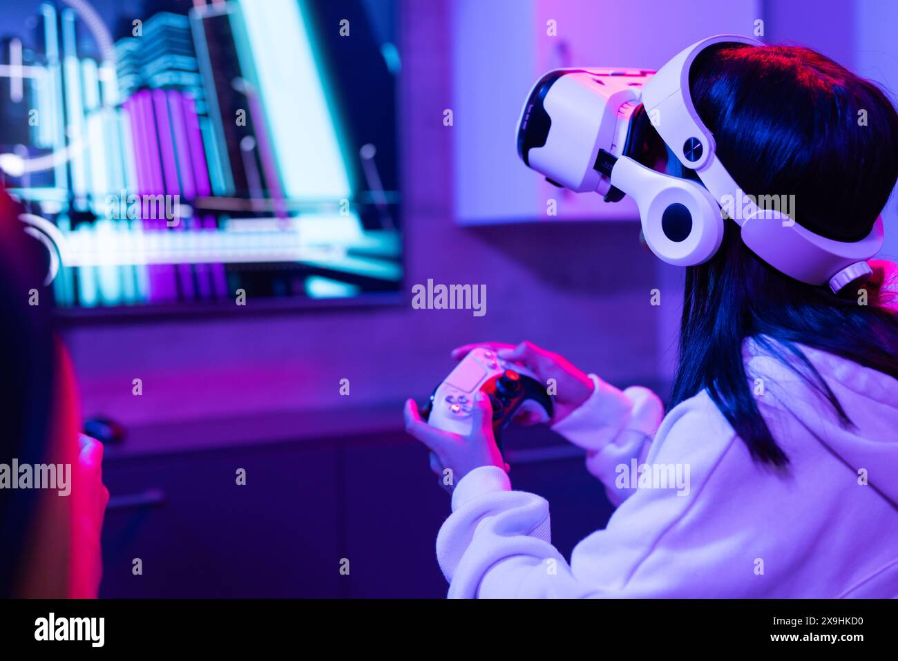 Jeunes sœurs biraciales, portant des casques VR, à la maison, jouant à des jeux vidéo Banque D'Images