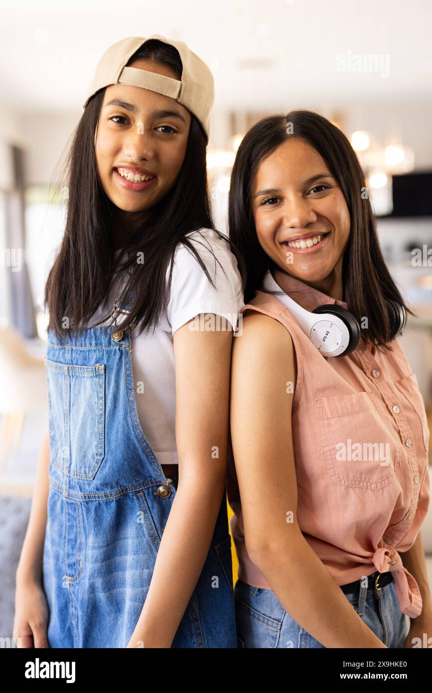 Jeunes sœurs biraciales souriantes à la maison, profitant d'une journée ensoleillée Banque D'Images