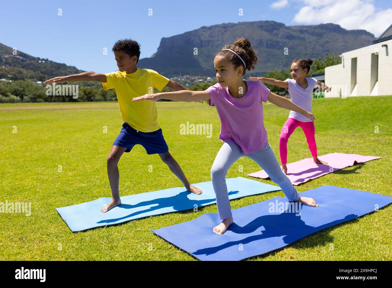 Les enfants biraciaux pratiquent le yoga à l'extérieur par une journée ensoleillée Banque D'Images