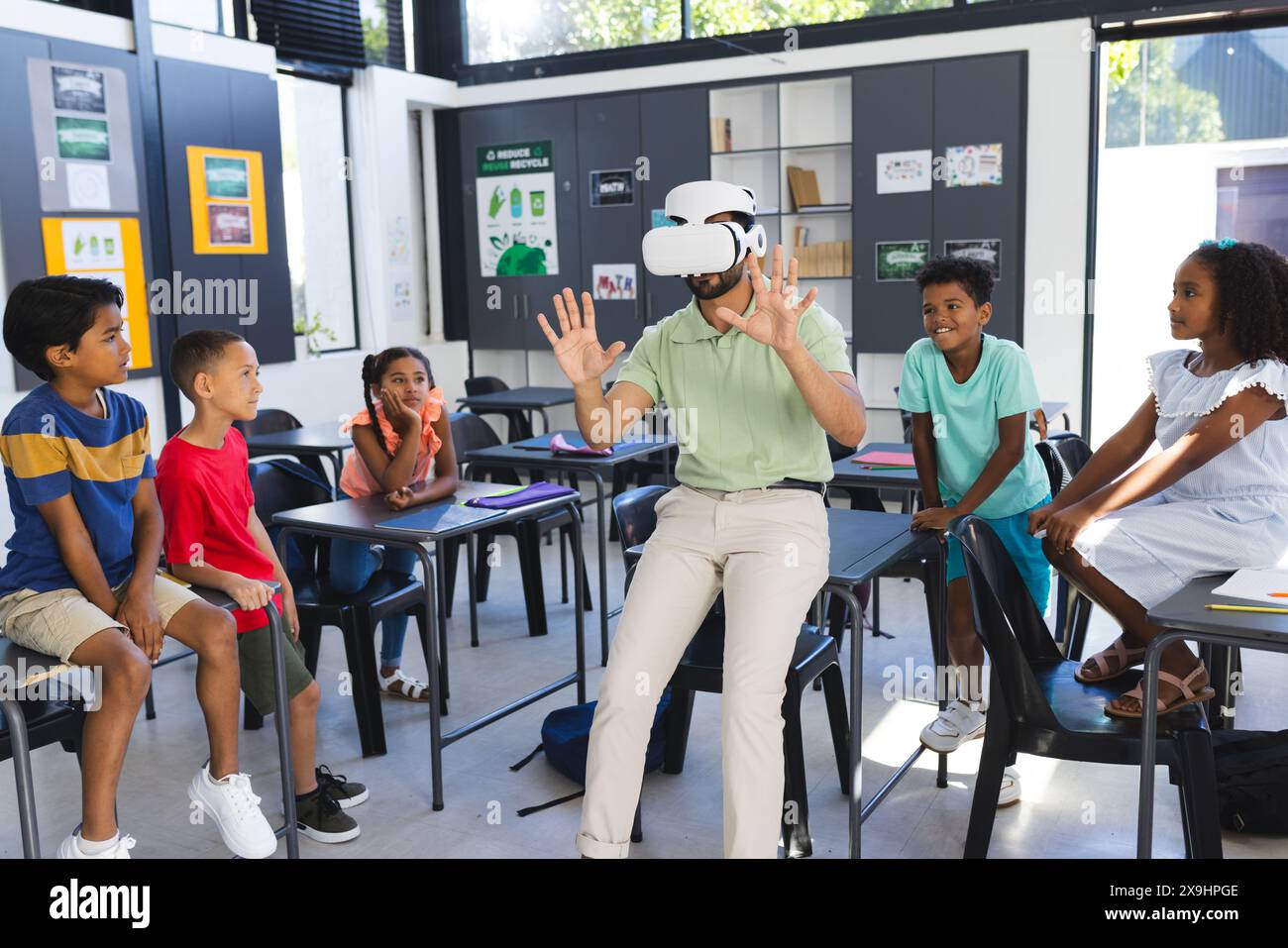 À l'école, un enseignant asiatique portant un casque VR se tient devant des étudiants biraciaux Banque D'Images