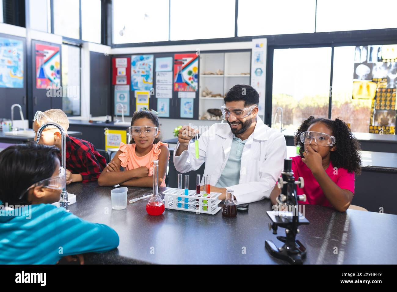 À l'école, professeur asiatique montrant l'expérience de chimie à divers élèves Banque D'Images