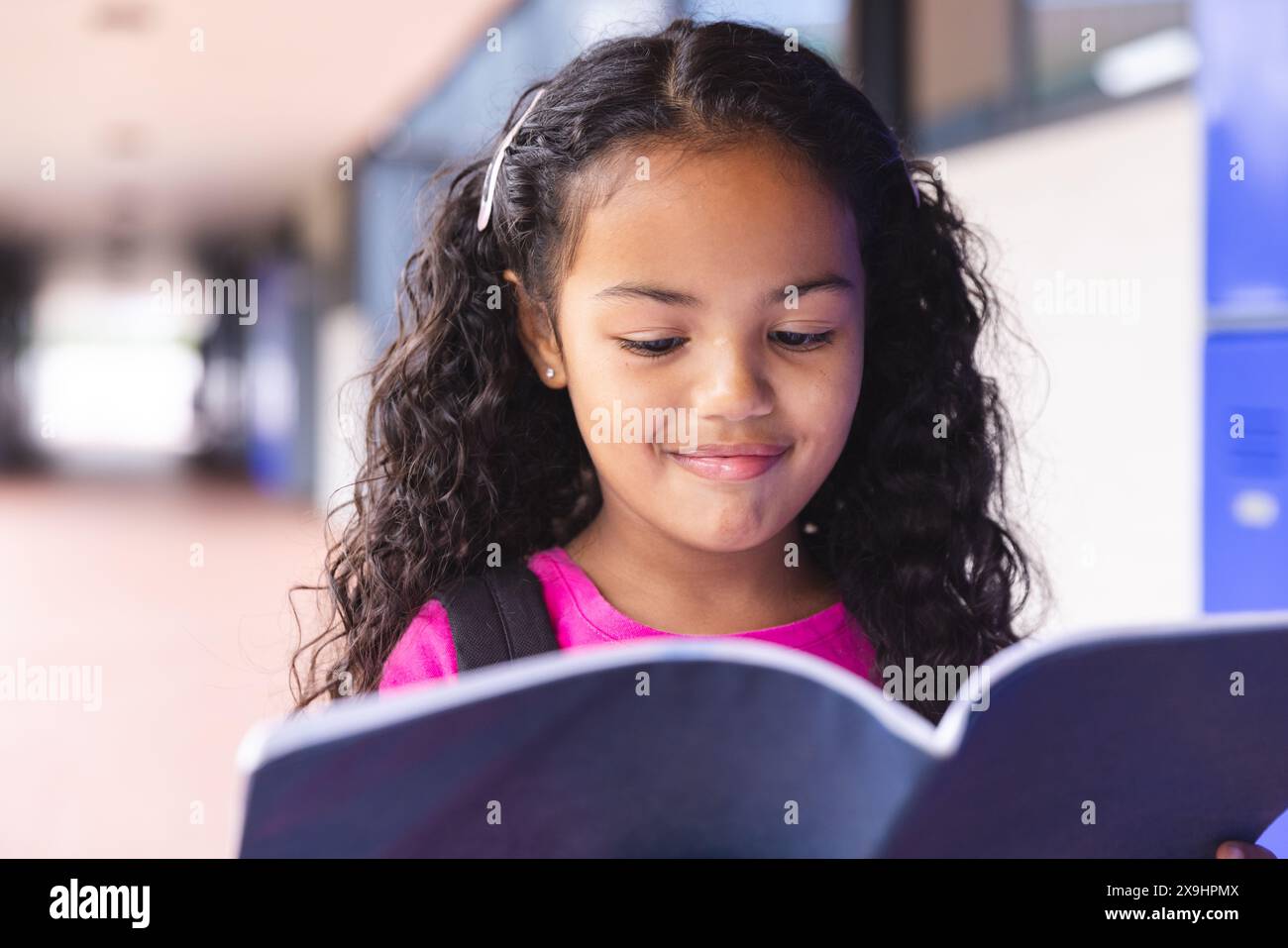 À l'école, à l'extérieur, étudiante biraciale lisant livre Banque D'Images