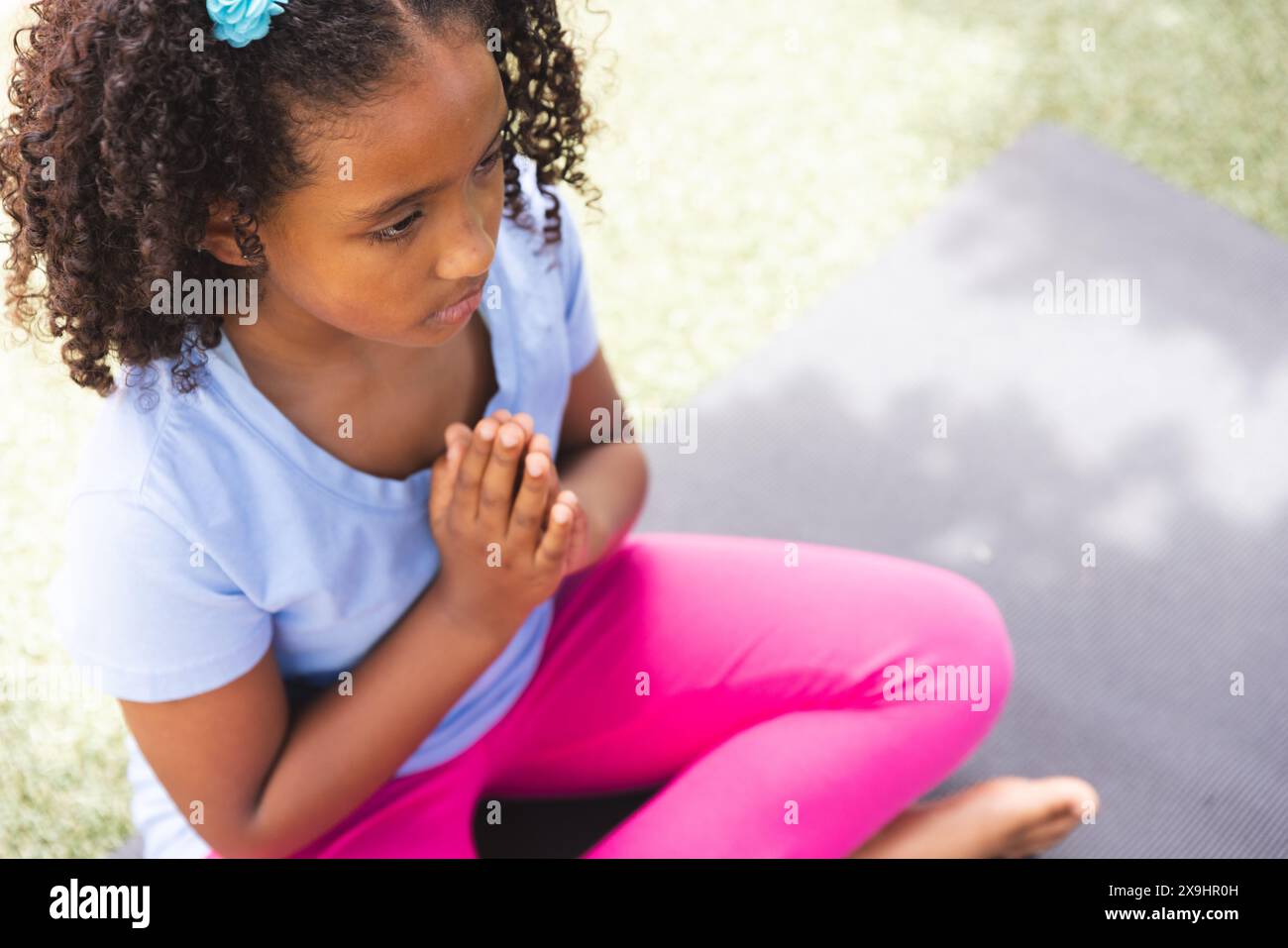 Une fille biraciale pratique le yoga à l'extérieur à l'école, avec un espace de copie Banque D'Images