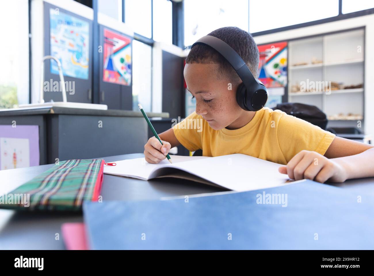 Biracial Boy se concentre sur le travail scolaire à l'école Banque D'Images