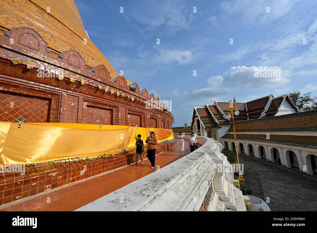 Des gens portant des offrandes, en contournant le chemin intérieur autour du cloître circulaire du gigantesque stupa Phra Pathom Chedi, Nakhon Pathom Banque D'Images