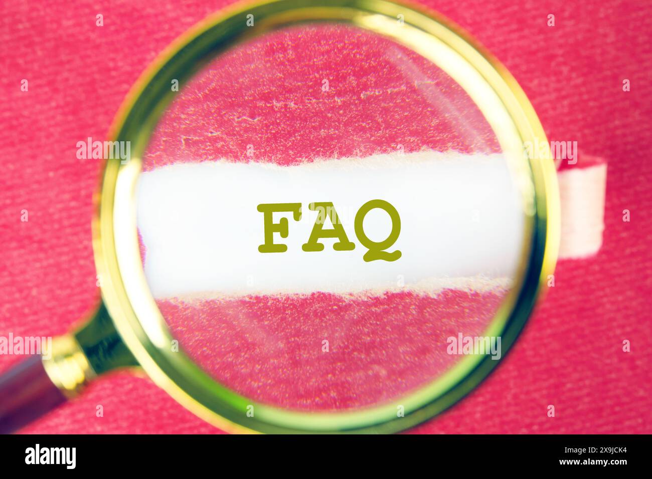 FAQ concept à travers une loupe sous un morceau de papier rouge déchiré Banque D'Images