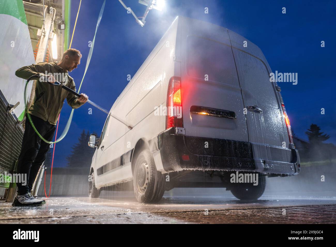 Homme lavant White Cargo Van la nuit Banque D'Images
