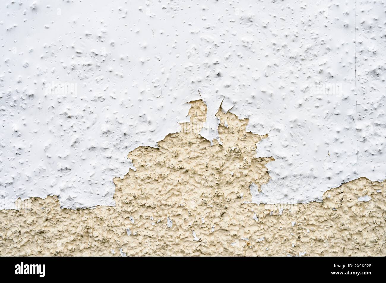 Peinture blanche endommagée qui s'écaille d'un mur de cailloux Banque D'Images