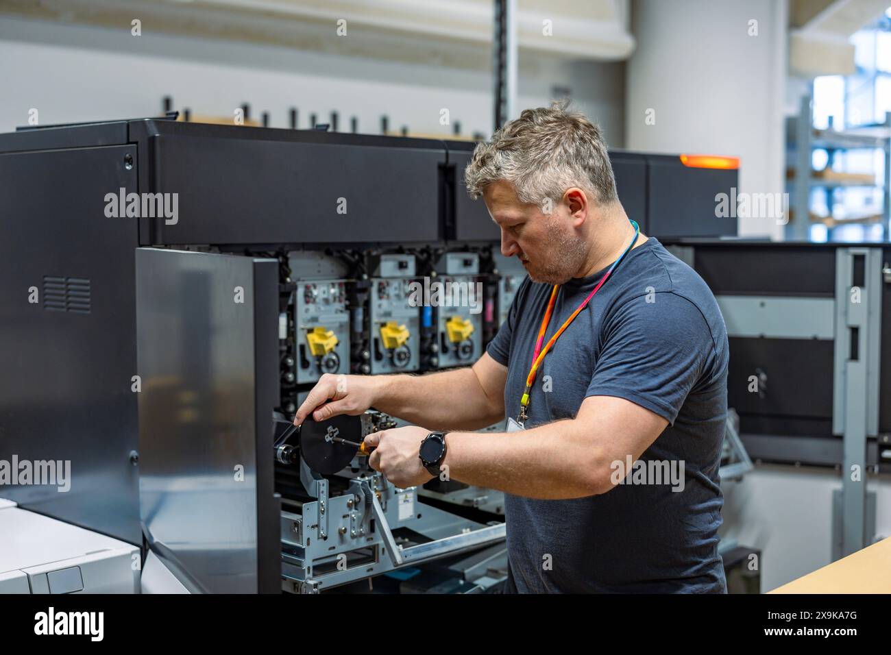 Ingénieur de maintenance dans une machine de fixation de maison d'impression Banque D'Images