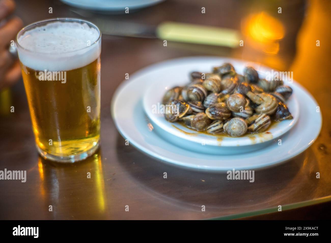 Un verre de bière et une assiette d'escargots de style andalou, un plat de tapas typique, servi dans une taverne de Séville. Banque D'Images