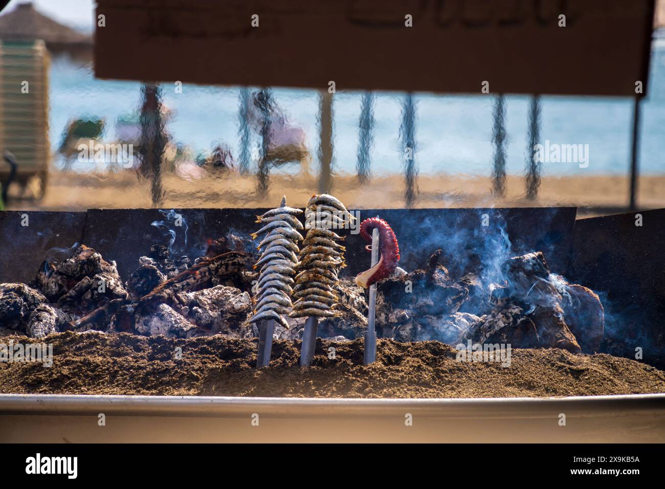 Malaga Beach avec la cuisine espagnole populaire, Espetos sur le grill. Les sardines sont placées sur des brochettes et grillées dans une fosse de barbecue en plein air à Málaga. Banque D'Images