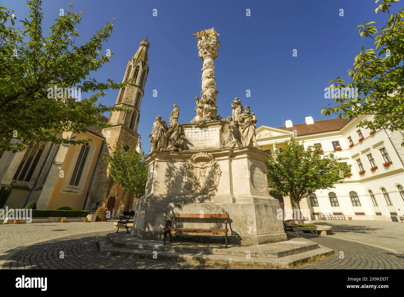 Gros plan de la statue de la Sainte Trinité, Szentháromság-szobor, avec l'église bénédictine de la Bienheureuse Marie, église de la chèvre, sur la place principale de Sopron, Hongrie. Banque D'Images