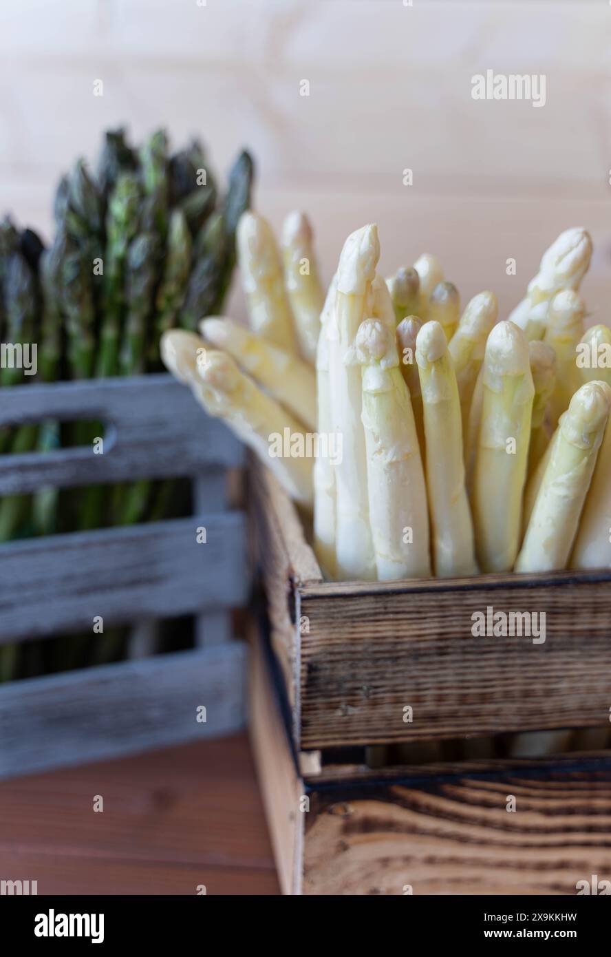 Gros plan d'une caisse brune d'asperges blanches à l'avant avec une caisse grise d'asperges vertes à l'arrière Banque D'Images