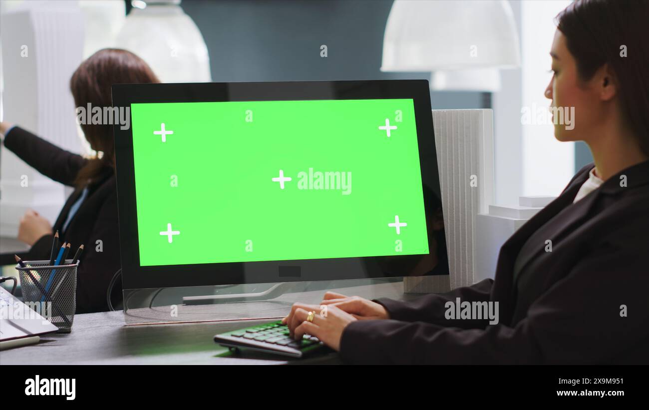 Concepteur CAO utilisant un PC avec écran vert dans la zone de la station de travail, examinant le moniteur avec la conception d'espace de copie vierge dans la société de démarrage. L'ingénieur utilise l'affichage chromakey isolé sur l'ordinateur. Banque D'Images